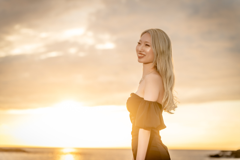 斜めに体を向けて夕日に笑顔を向ける