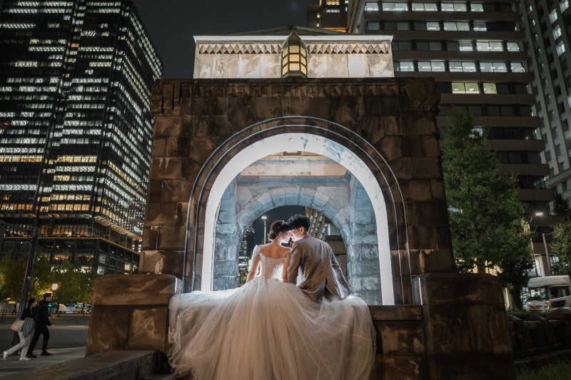 アーチの下で寄り添うドレスとスーツの背中