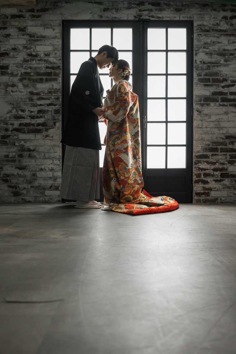 レンガ壁とフランス扉を背に向かい合う立ち姿