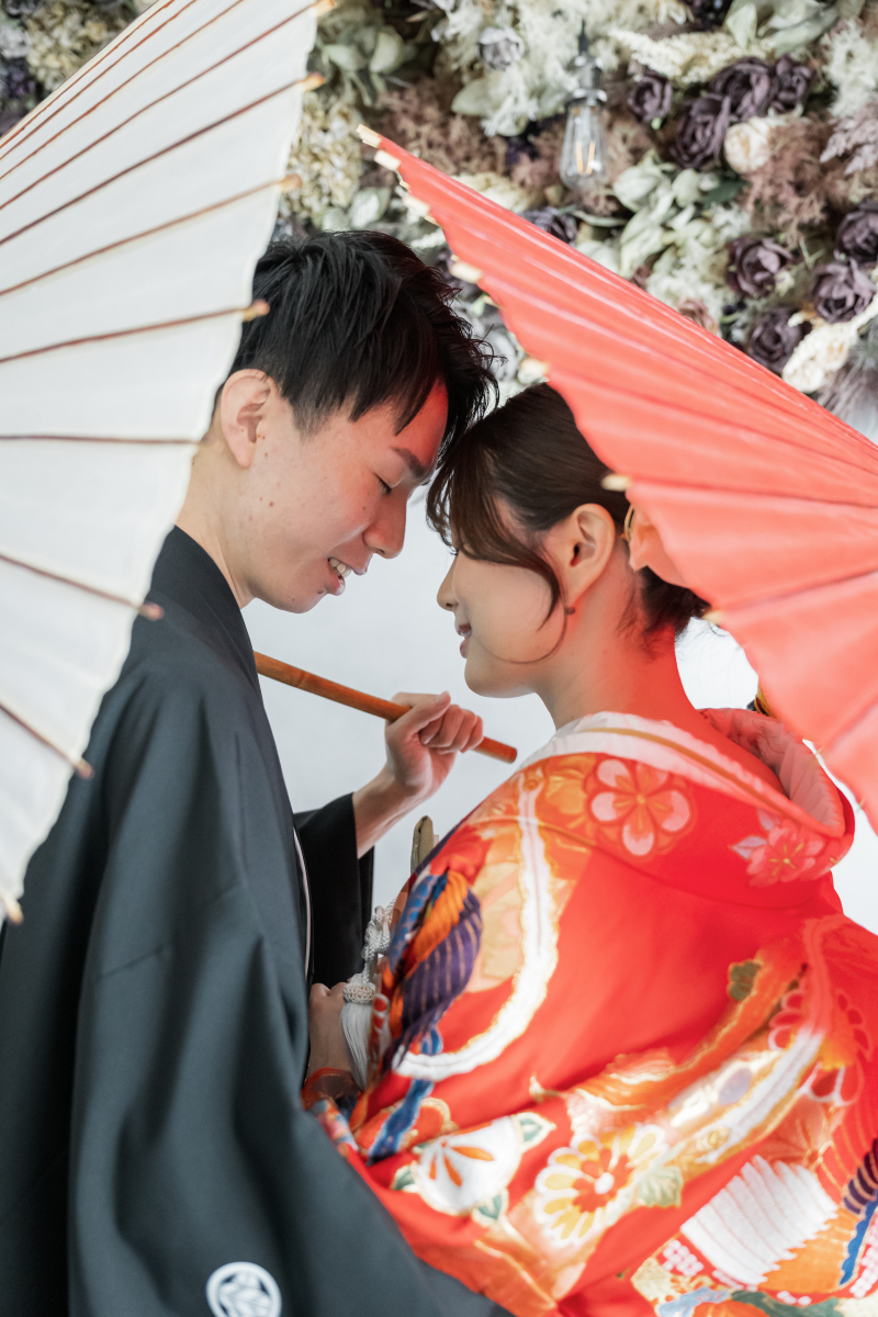 赤と白の番傘を手に額を寄せ合う