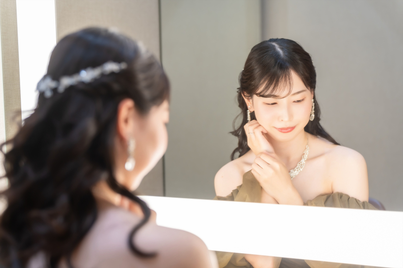 鏡の前でイヤリングを添える手元と表情
