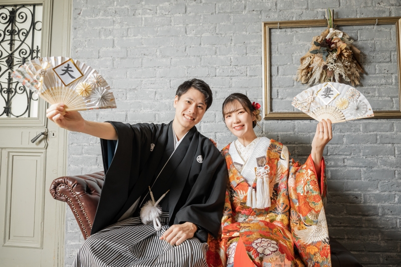 扇子を高く掲げ笑顔で並ぶ晴れやかな色打掛