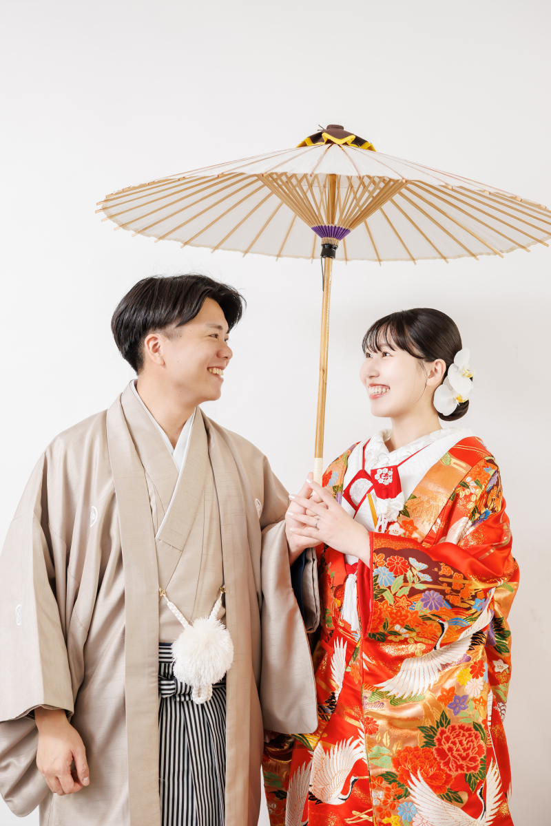 和傘の下で笑顔を向け合う温かな表情