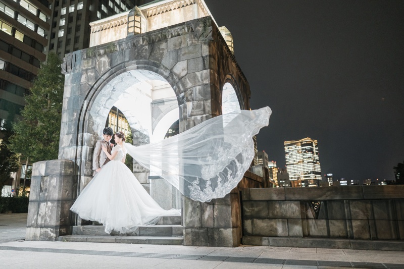 大きくなびくベールをまとい石のアーチに寄り添う