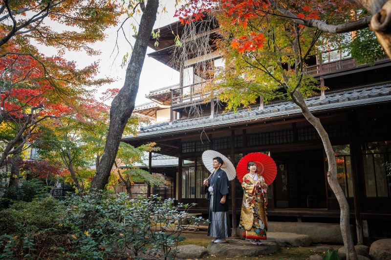 古民家と紅葉を背に並ぶ二人の静けさ
