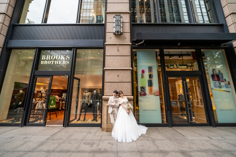 ガラス張りのビル前で寄り添う白いドレス