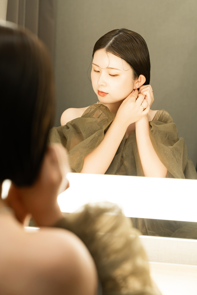イヤリングをつける指先と鏡の花嫁