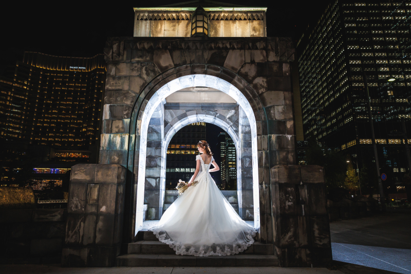 ブーケを持ちアーチに立つ白ドレスの花嫁