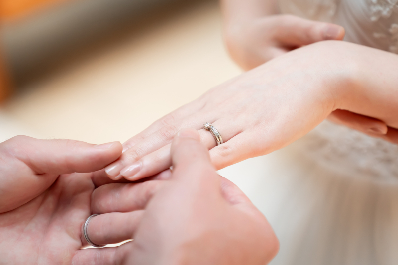 薬指に指輪をはめる繊細な手元のふたり