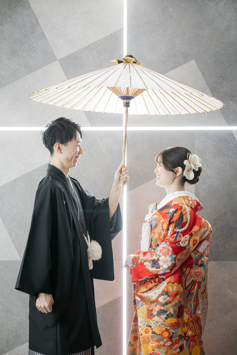 白番傘を高く掲げて新婦様と笑顔を向け合う新郎様