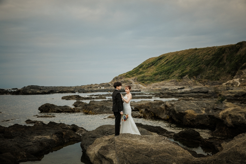 岩場で向かい合うドレスとタキシード