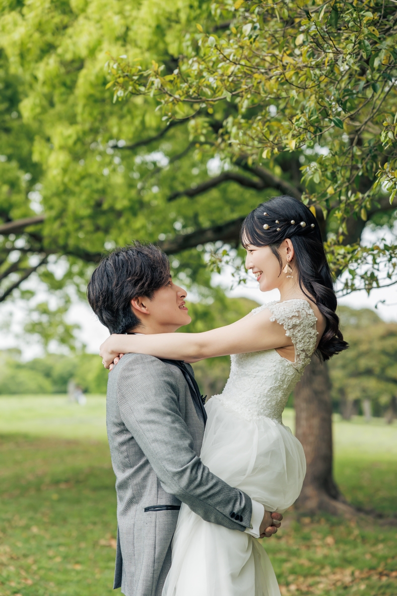 大きな木の下で向かい合い笑顔を交わす二人