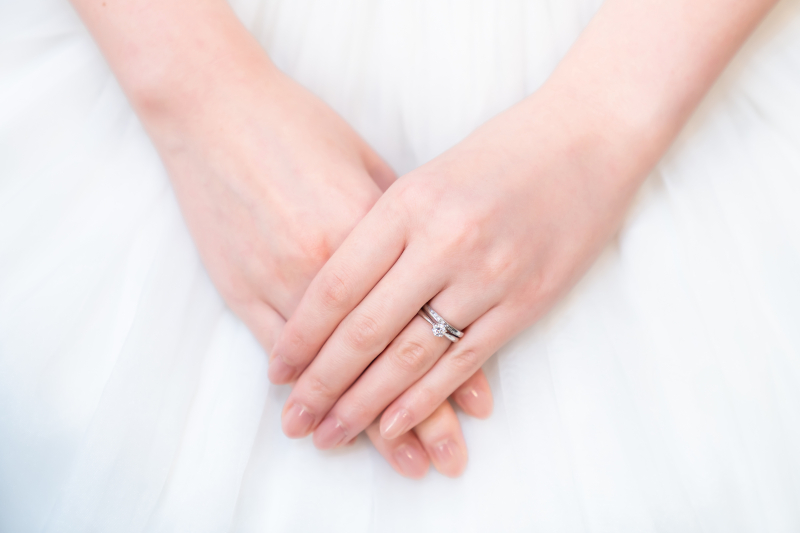 白いドレスに重なる指輪の手元