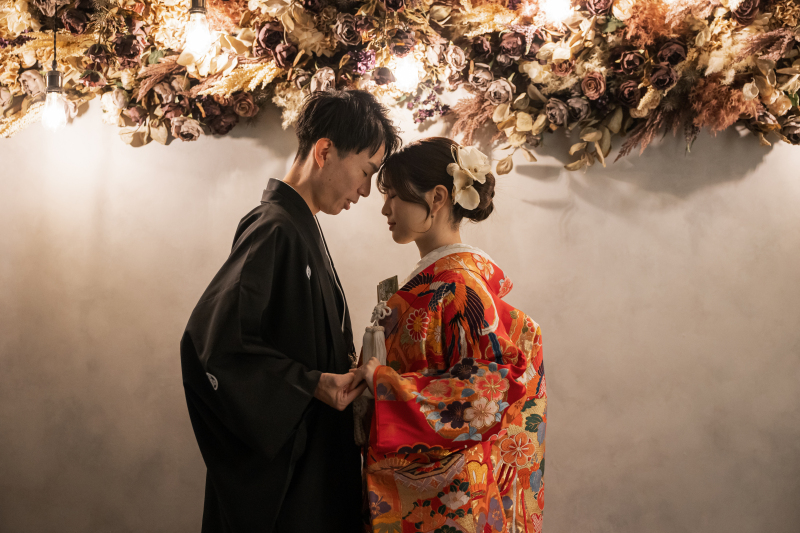 黒紋付きと赤打掛で向かい合い額を近づける