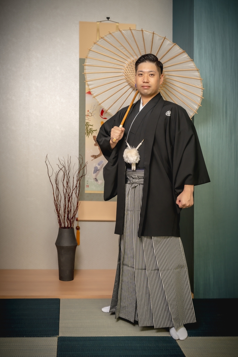 番傘を背負い堂々と佇む紋付袴の貫禄