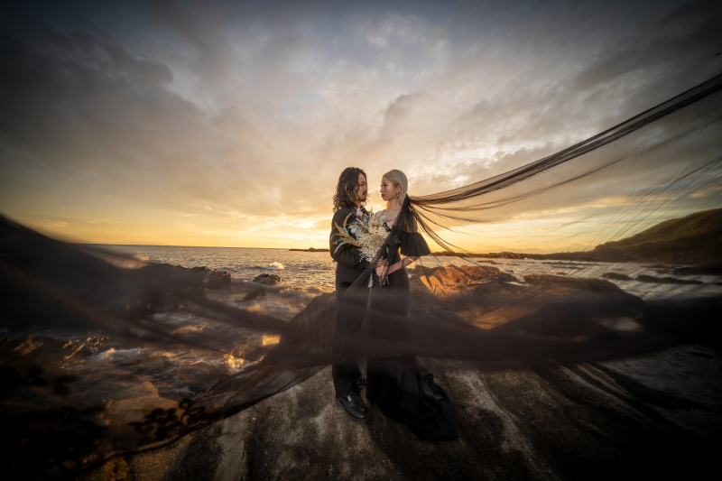 ベールをまとい夕焼けに包まれるふたり