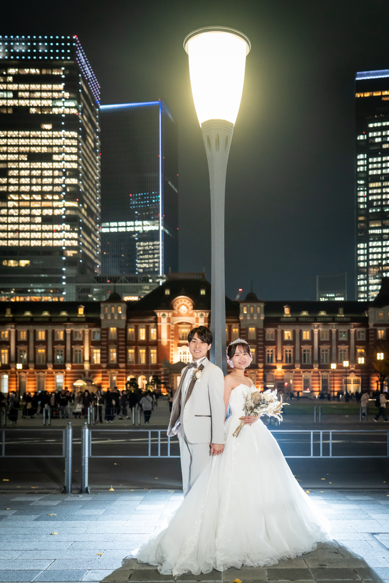 夜の街灯の下に並ぶドレスと東京駅の輝き