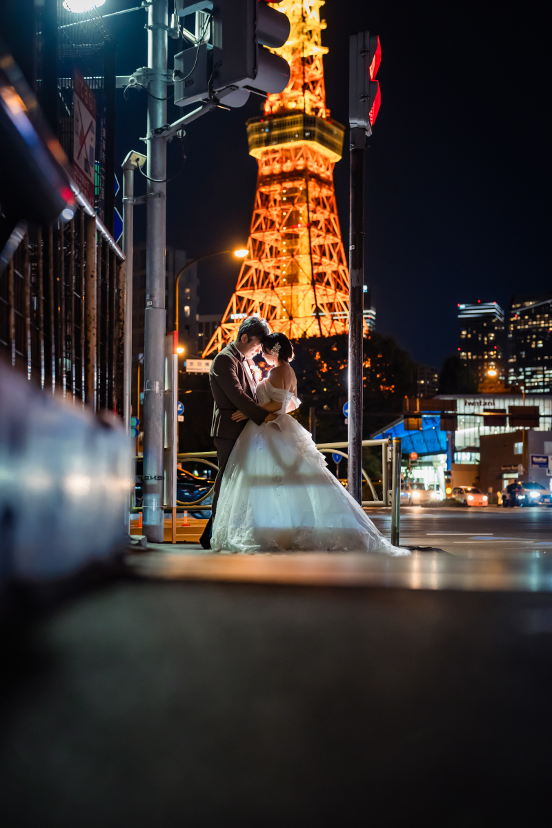 低アングルでタワーを背に抱き合う