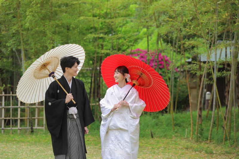竹林で和傘を手に見つめ合う和装姿の自然なおふたり