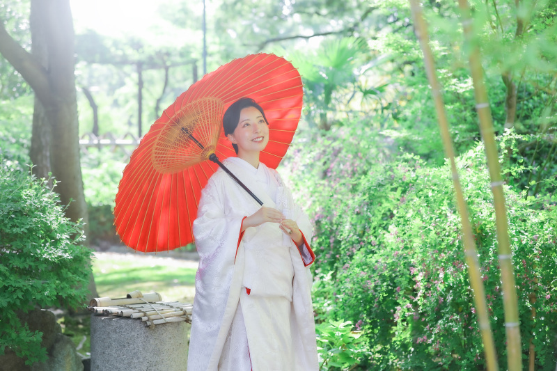 赤い番傘とやわらかな光に包まれた白無垢花嫁様の姿