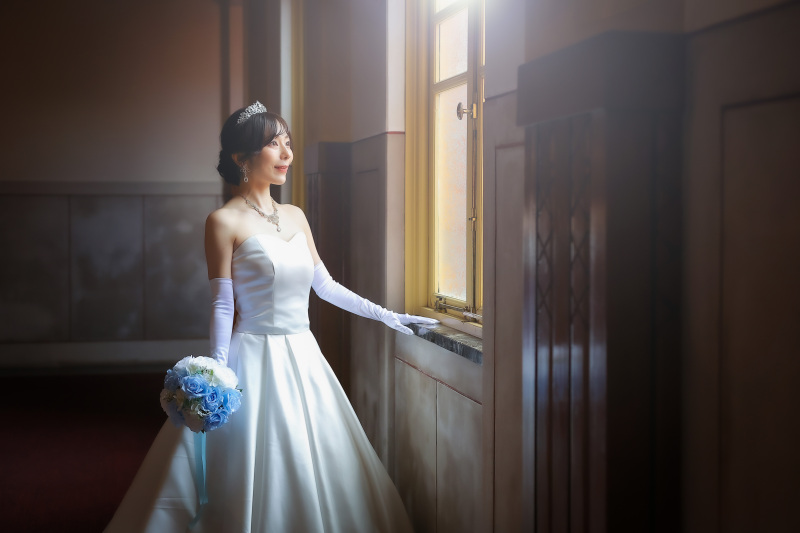 館内の柔らかな光に包まれた新婦様の窓辺ショット