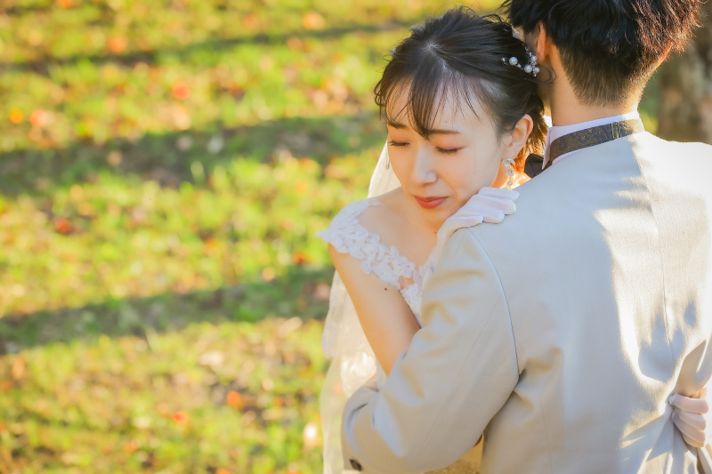 夕方の光に包まれて抱きしめ合うおふたりの洋装写真