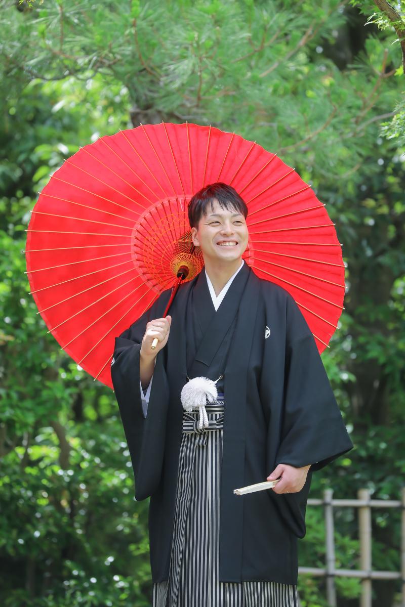 赤い番傘が映える新郎様らしい笑顔の和装ソロカット