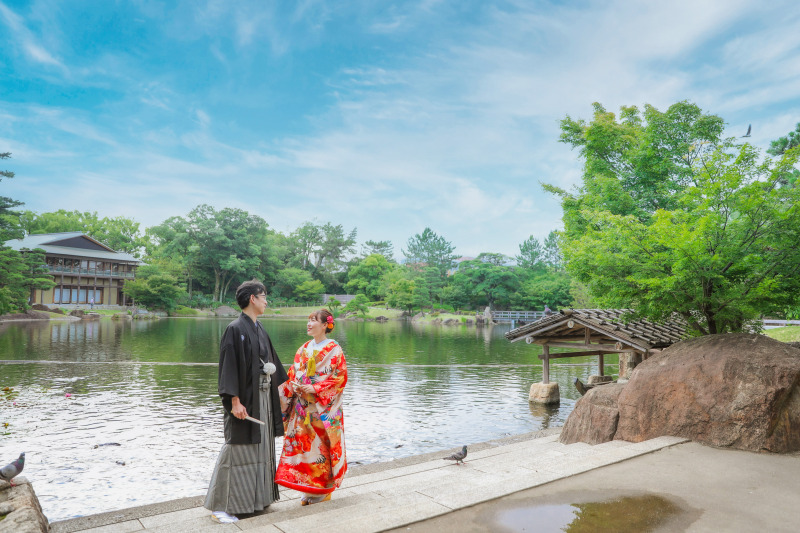 青空のロケーションの下で徳川園で色打掛前撮り