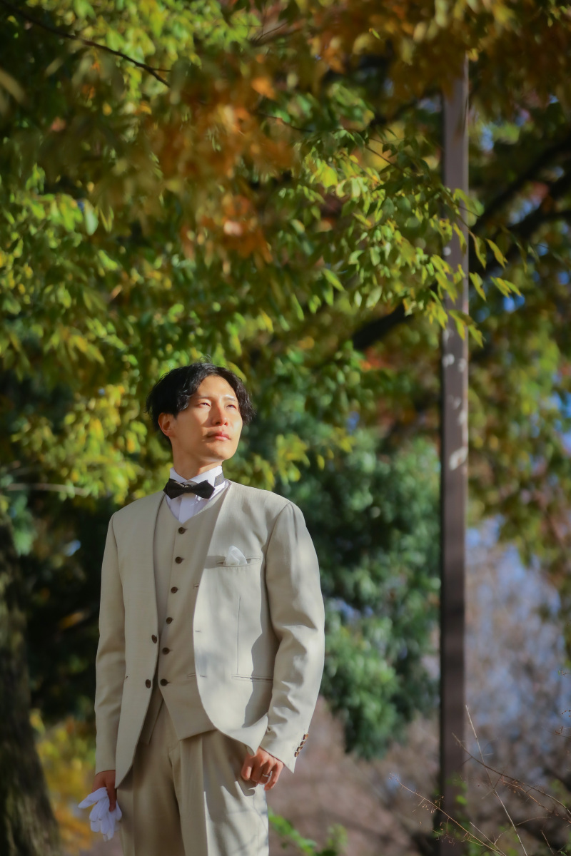 木陰に立つ新郎様のタキシード姿が凛々しいソロ写真