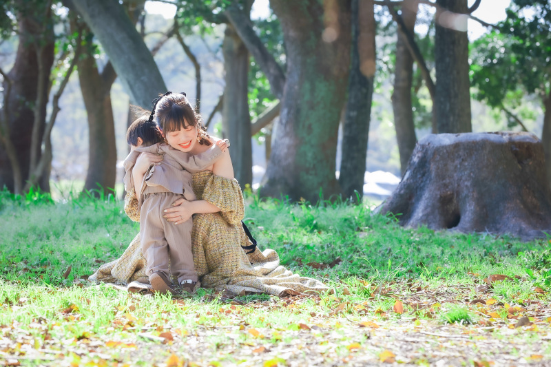 木陰でお子様を抱きしめる花嫁様のカラードレス写真