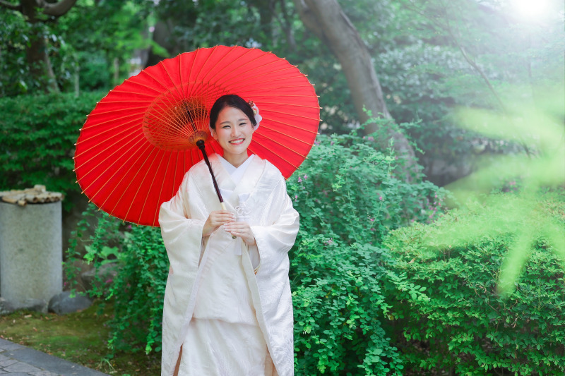 白無垢と赤い和傘が映える中村公園での庭園ショット