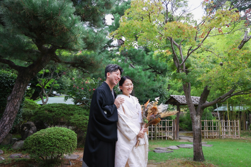 新緑の庭園で新郎新婦様が寄り添う和装ツーショット