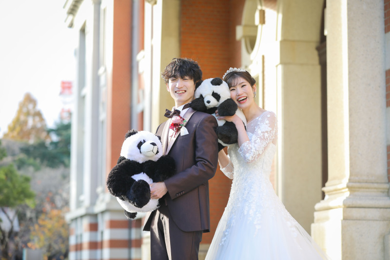 パンダのぬいぐるみと洋装衣装で笑顔のツーショット