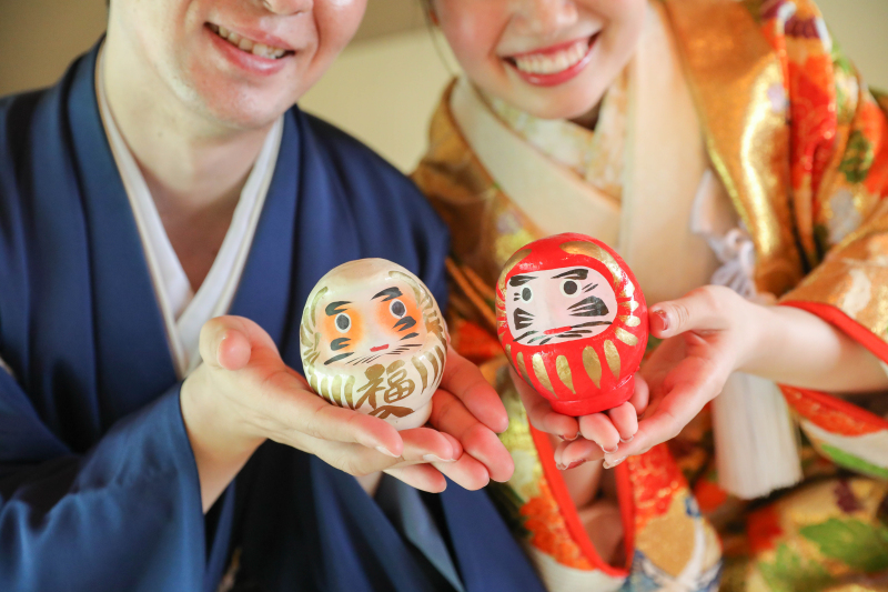 地元名産のダルマを持って