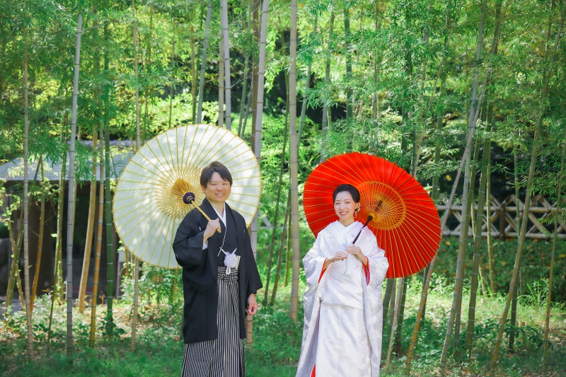 竹林に映える白と赤の番傘で楽しむおふたりの和装姿