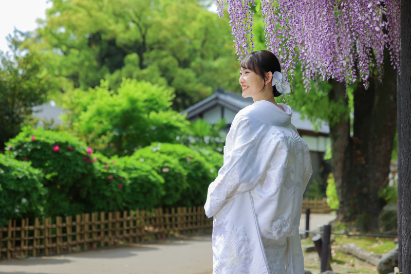 藤の花の下で振り向く白無垢花嫁様のやさしい後ろ姿