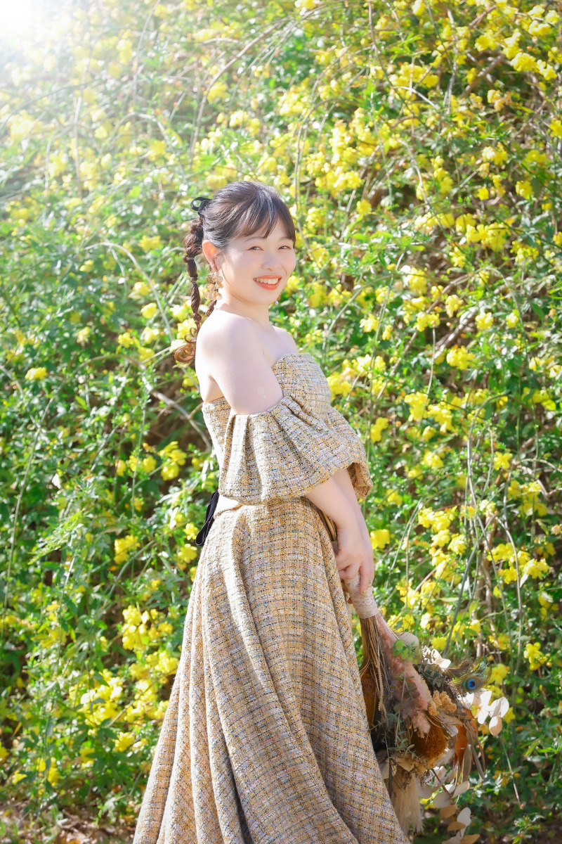 花咲く緑を背景にしたカラードレス花嫁のソロカット