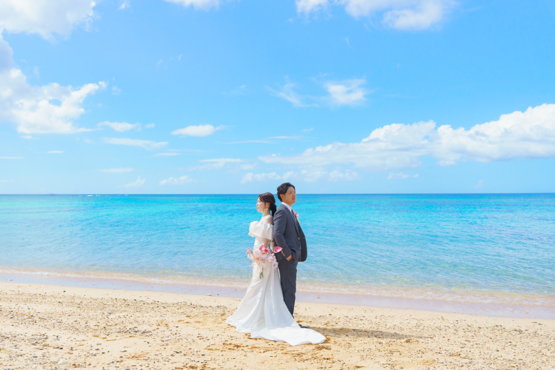 青い海を背に、背中合わせに立つふたり