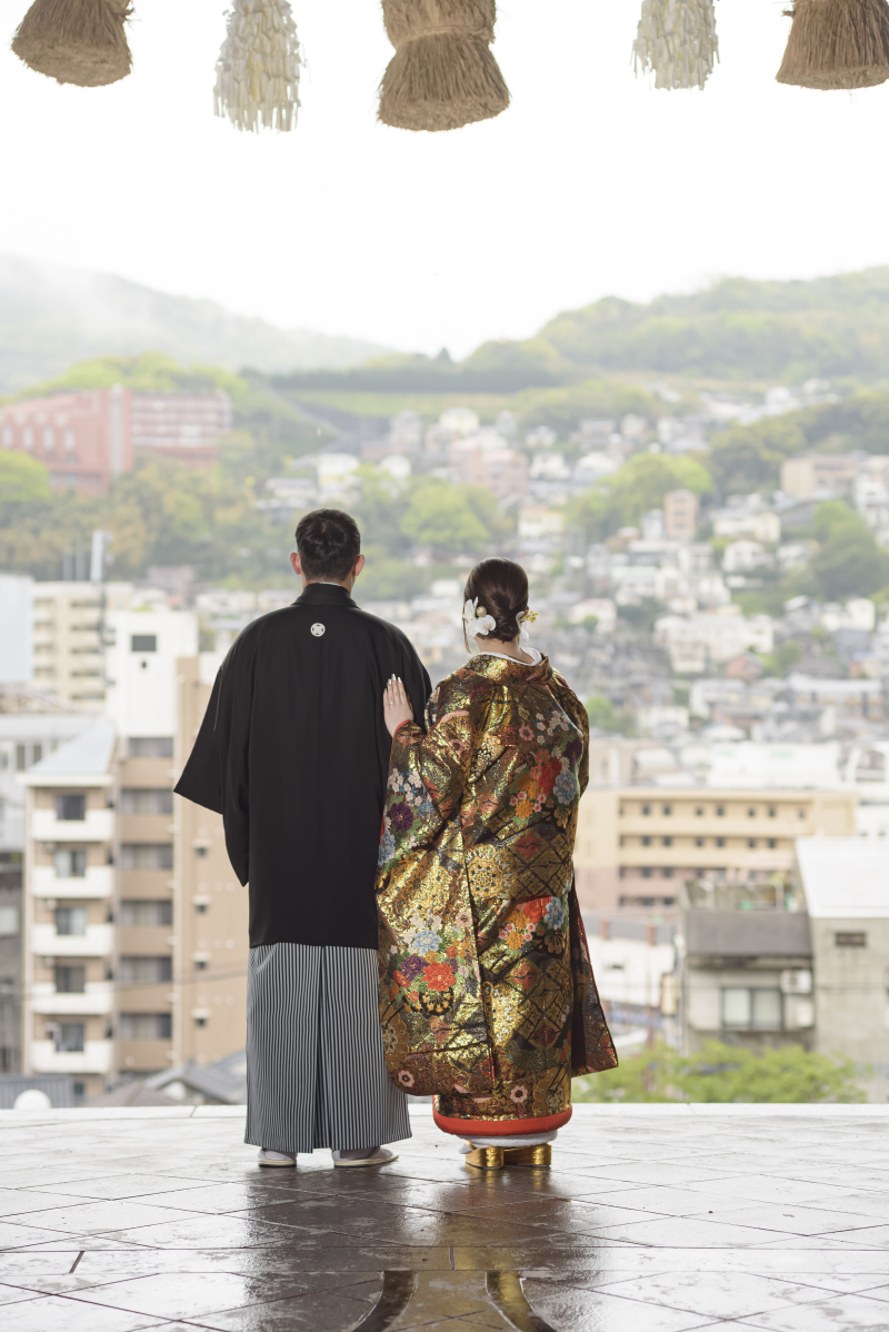 長崎の街並みを背に