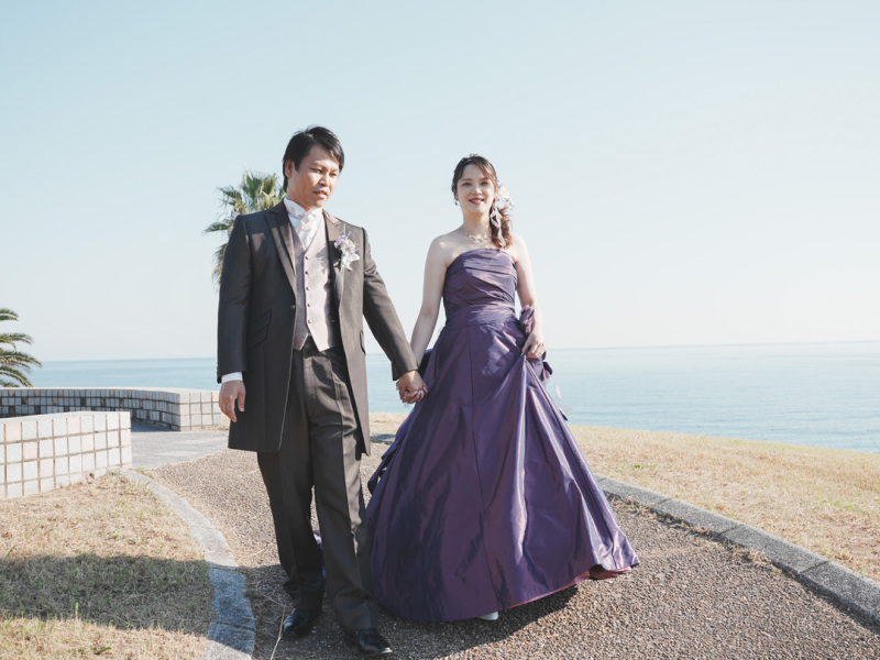 紫のドレスとブラウンタキシードに移る青色の海