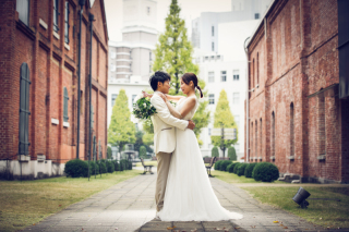 赤レンガをバックにバージンロードを意識した１枚。衣装のナチュラル感とお二人のクラシックな写真イメージを活かしてシンプルなポージングながらもインパクトのあるショットを心がけました