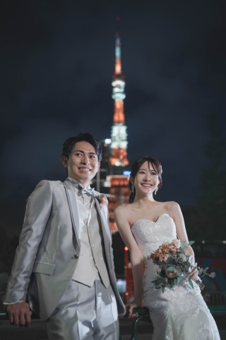 ライトアップされた夜の東京タワーを背に、明るい笑顔を見せる新郎新婦。都会ならではのロマンチックな夜景が、お二人の幸せに満ちた表情をより一層華やかに引き立てます。