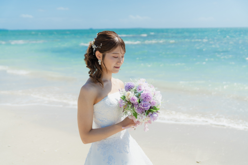 海風の中でブーケを眺める新婦様の素敵なショット
