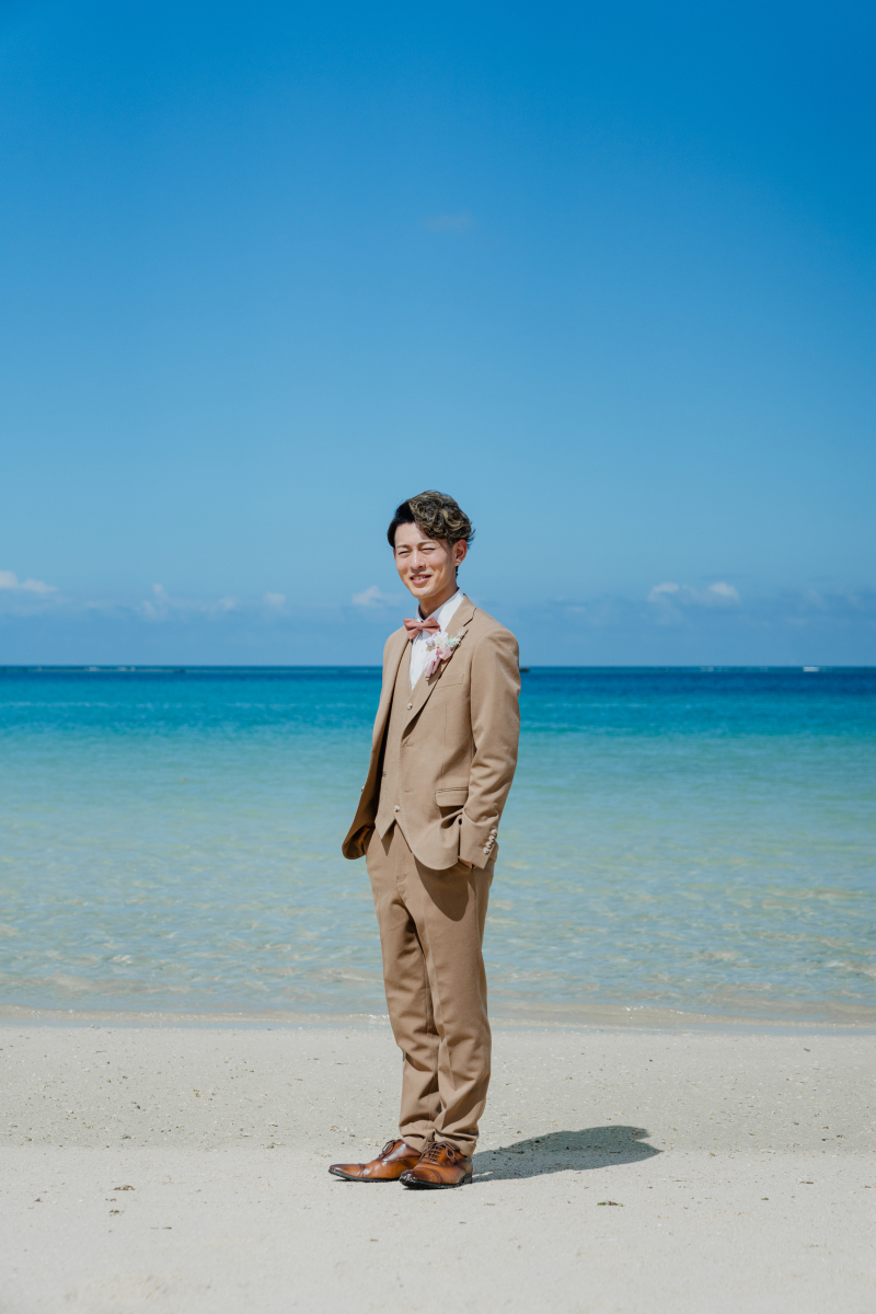 海の色に映えてふっと笑う新郎の柔らかな表情