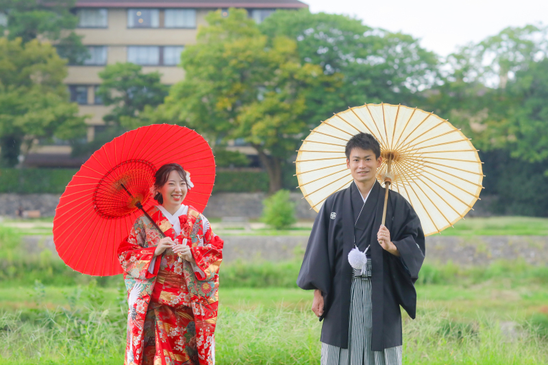 鴨川を背景に番傘を持って