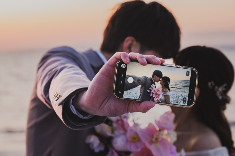 スマホの画面越しに見つめ合う二人を捉えたカット