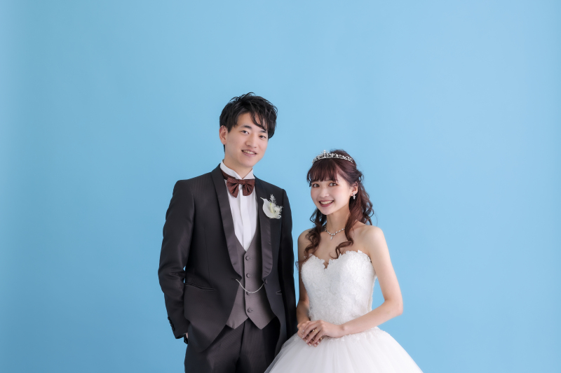 ブルーの背景をバックにドレス姿が映えるカット