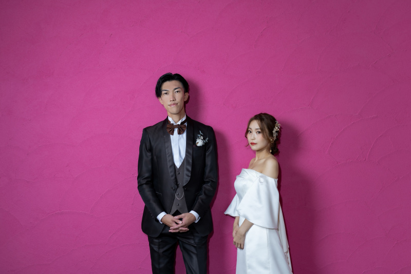 ビビットなカラーの壁の前でおしゃれなカット