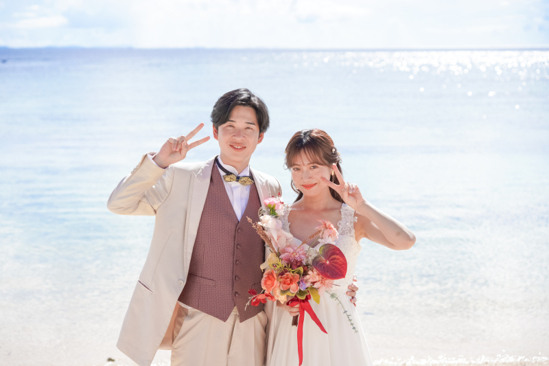 ビーチでブーケを持ちながらピース