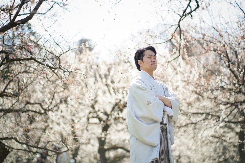 白紋付き袴が映える。梅林に立つ新郎様の凛々しい姿